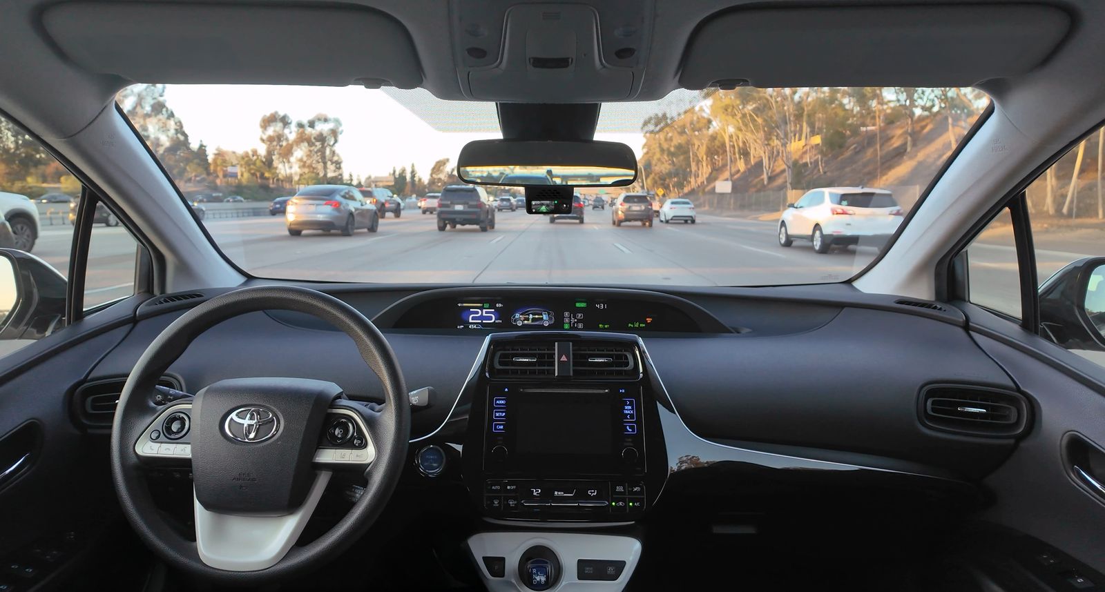 comma four mounted beneath the rearview mirror during a highway drive